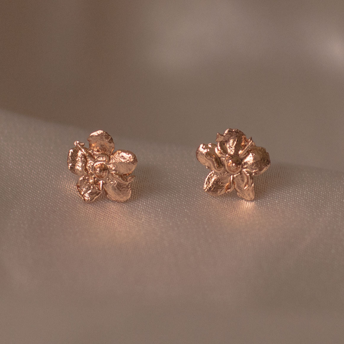 Aretes Topo Mini Flor Sauco en bronce bañado en oro de 24k, mostrando la delicadeza y la forma única de la flor natural.