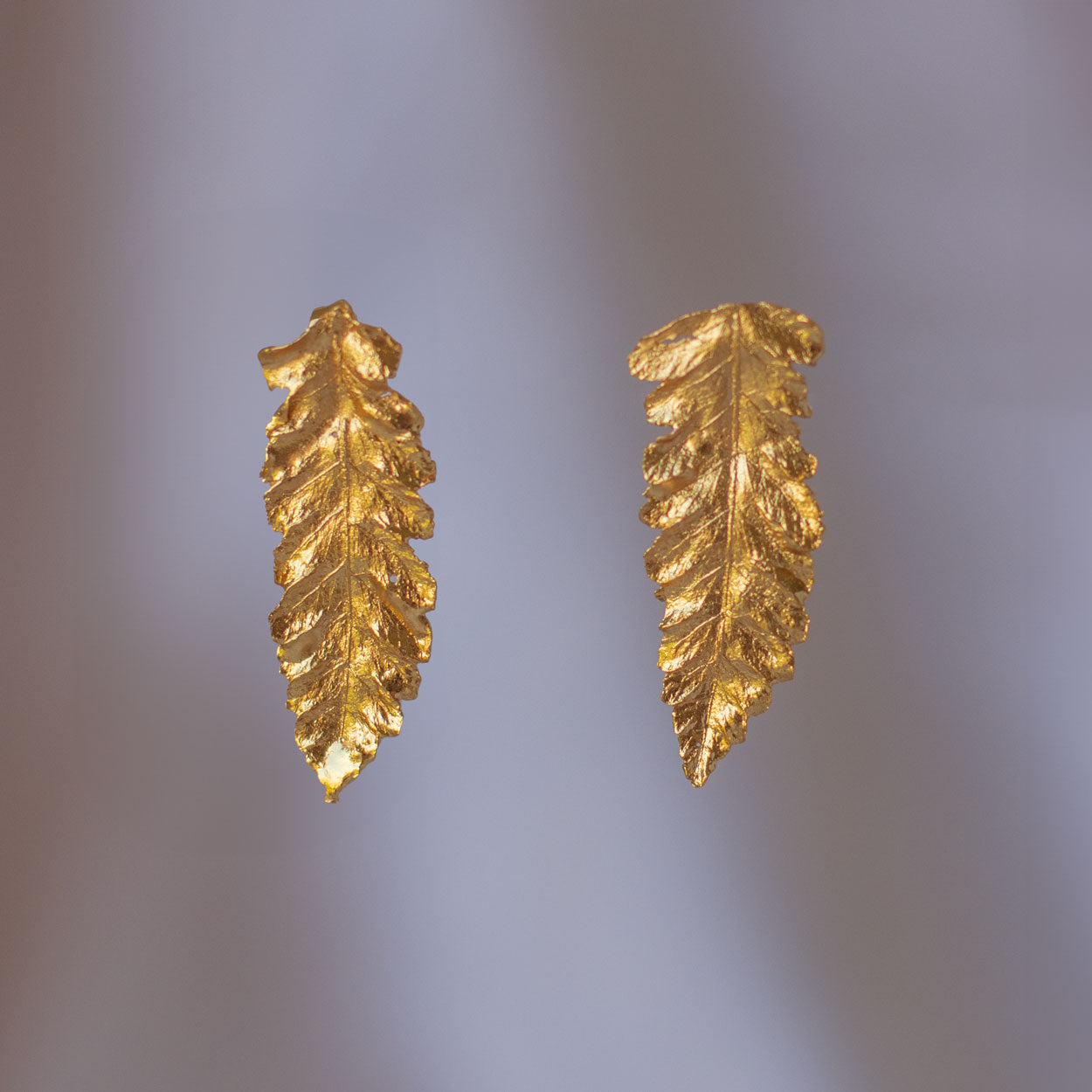 Aretes Topo Helecho Canela de bronce enchapado en oro de 24k, cada uno reflejando una hoja única del jardín de orquídeas