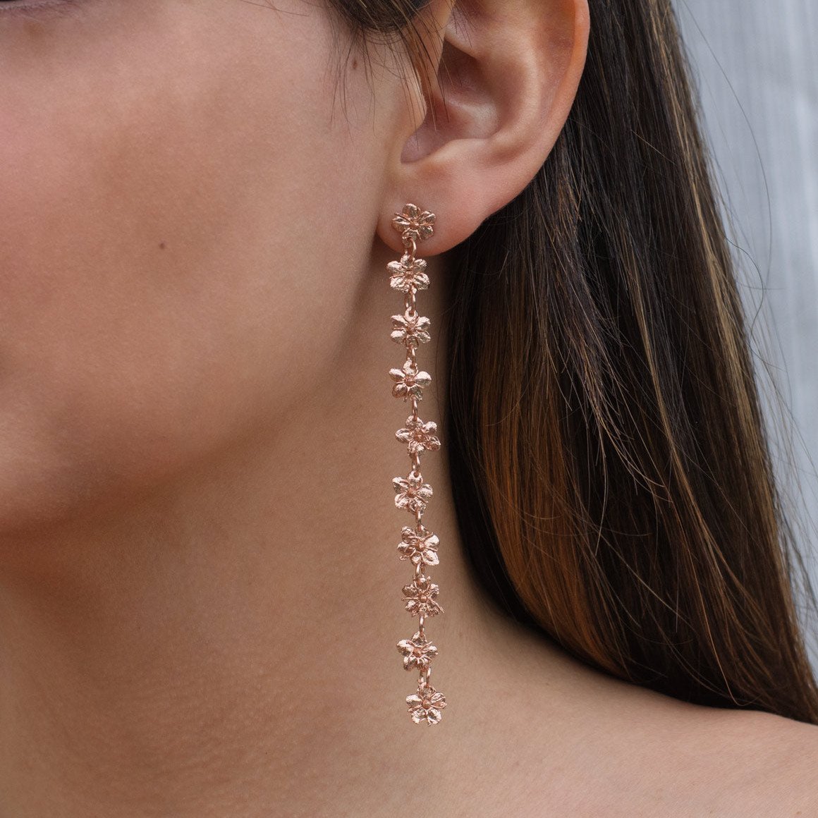 Joyería artesanal de aretes largos con flores de sauco inmortalizadas en oro de 24k