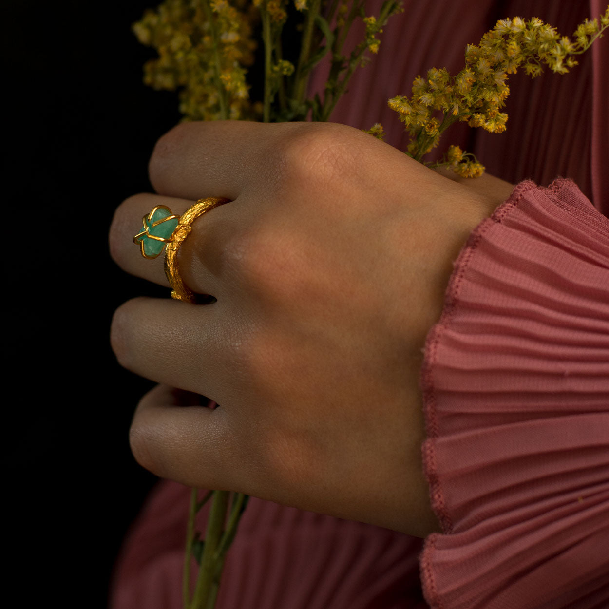 Anillo Ramita con Esmeralda en bronce bañado en oro de 24k, destacando la textura natural de la ramita y el brillante verde de la esmeralda