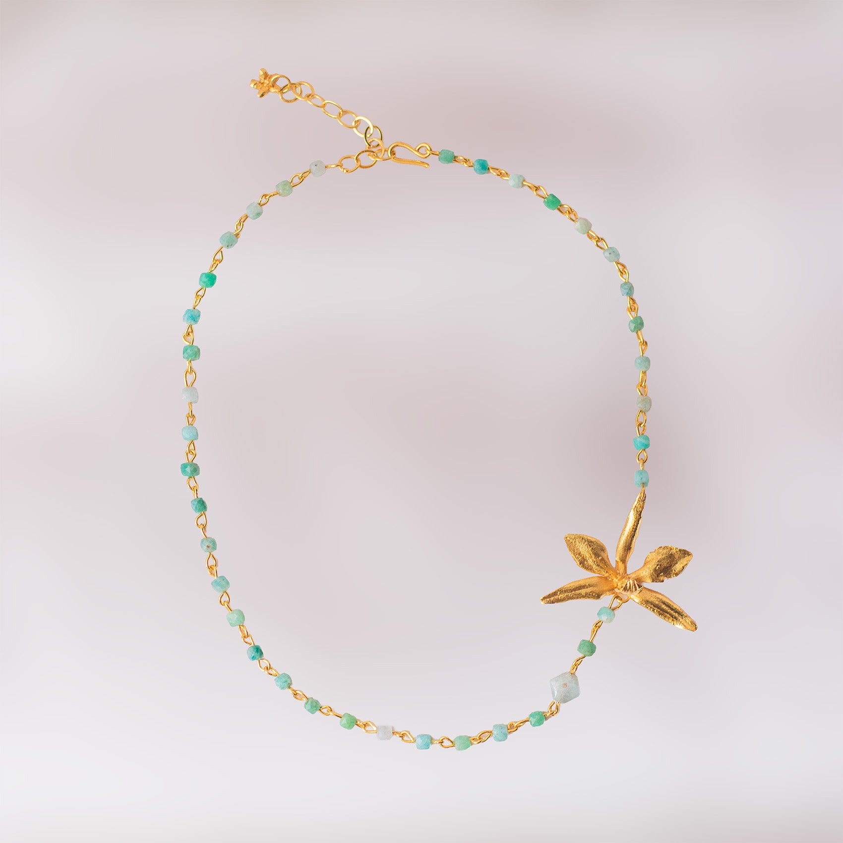Collar de cuarzo aguamarina y orquídea natural inmortalizada en bronce con baño de oro, joyería artesanal colombiana.