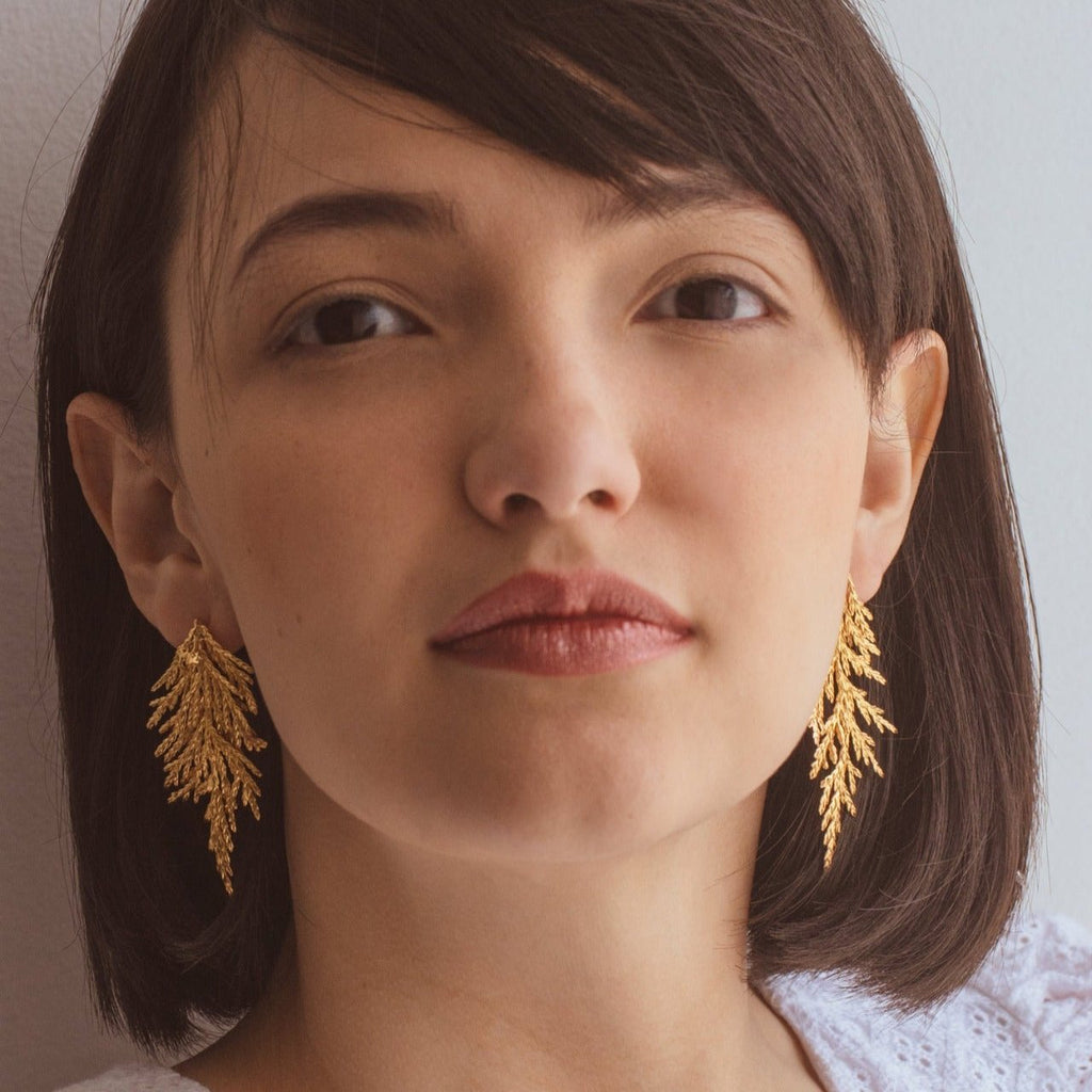 Aretes Hoja Pino Grande en bronce bañado en oro de 24k, destacando la belleza natural de las hojas de pino inmortalizadas