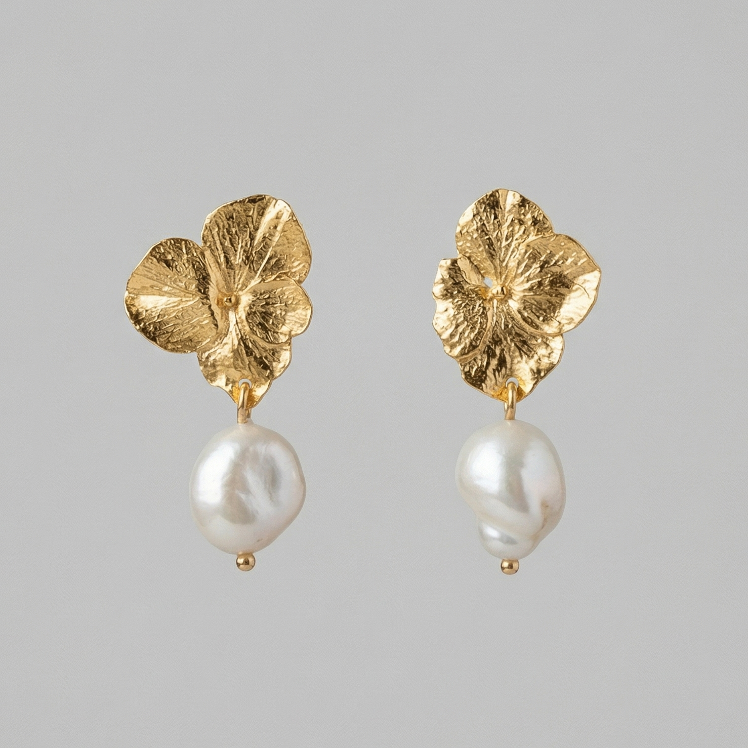 Par de aretes topo hortensia dorados con perla barroca, detalle de joyería artesanal colombiana Liz de la Cruz