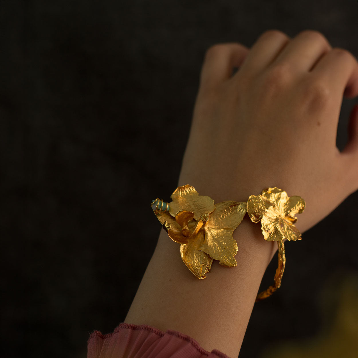 Brazalete Orquídea Phalaenopsis Hortensia Esmeralda en bronce bañado en oro de 24k, destacando flores naturales y una esmeralda colombiana