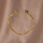Brazalete Ramita Palma Esmeralda en bronce bañado en oro de 24k, adornado con morralla de esmeralda colombiana, mostrando la forma natural de las ramitas de palma inmortalizadas