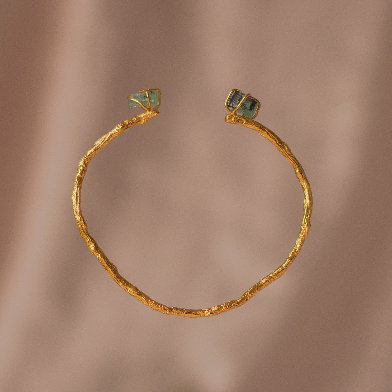 Brazalete Ramita Palma Esmeralda en bronce bañado en oro de 24k, adornado con morralla de esmeralda colombiana, mostrando la forma natural de las ramitas de palma inmortalizadas