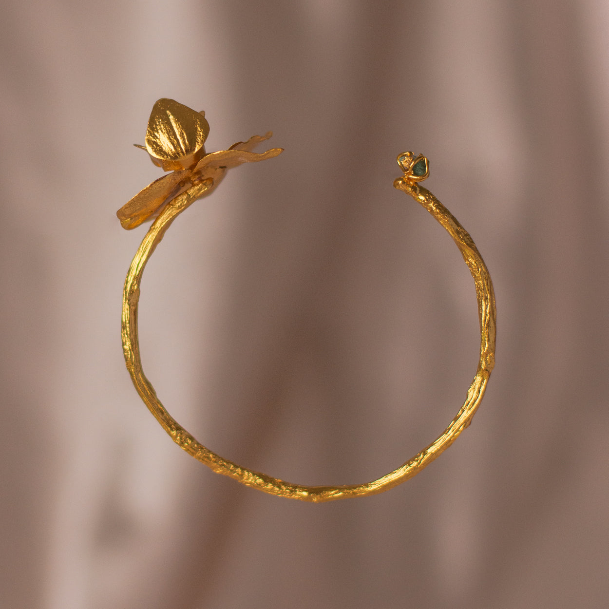 Brazalete Orquídea Phalaenopsis Baby Esmeralda en bronce bañado en oro de 24k, destacando la belleza única de las orquídeas y ramas inmortalizadas con detalles de esmeralda colombiana