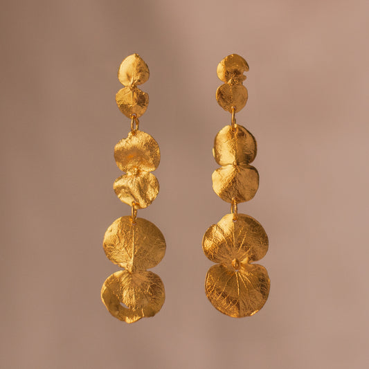 Aretes Largos Tres Eucaliptos en bronce bañado en oro de 24k, resaltando la delicadeza y el diseño único de las hojas naturales