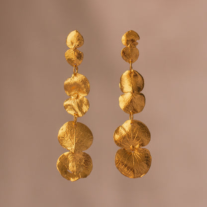 Aretes Largos Tres Eucaliptos en bronce bañado en oro de 24k, resaltando la delicadeza y el diseño único de las hojas naturales