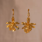 Aretes Candonga Orquidea Odontoglossum Pino Esmeralda en bronce bañado en oro de 24k, destacando la belleza única de las flores y hojas inmortalizadas con detalles de esmeralda.
