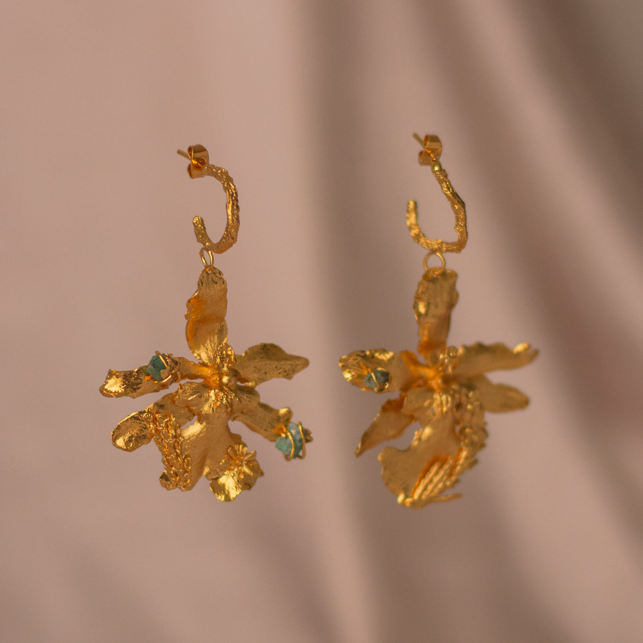 Aretes Candonga Orquidea Odontoglossum Pino Esmeralda en bronce bañado en oro de 24k, destacando la belleza única de las flores y hojas inmortalizadas con detalles de esmeralda.