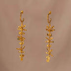 Aretes Aro Candonga Tres Orquídeas Oncidium Esmeraldas en bronce bañado en oro de 24k, adornados con morralla de esmeralda colombiana, mostrando la belleza natural de las orquídeas oncidium y las ramitas de palma inmortalizadas