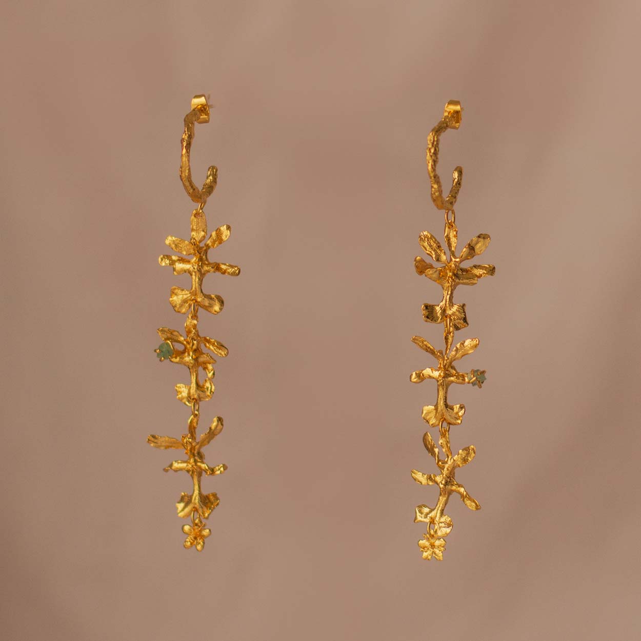 Aretes Aro Candonga Tres Orquídeas Oncidium Esmeraldas en bronce bañado en oro de 24k, adornados con morralla de esmeralda colombiana, mostrando la belleza natural de las orquídeas oncidium y las ramitas de palma inmortalizadas