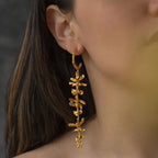 Aretes Aro Candonga Tres Orquídeas Oncidium Esmeraldas en bronce bañado en oro de 24k, adornados con morralla de esmeralda colombiana, mostrando la belleza natural de las orquídeas oncidium y las ramitas de palma inmortalizadas