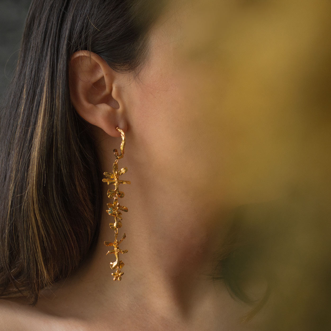 Aretes Aro Candonga Tres Orquídeas Oncidium Esmeraldas en bronce bañado en oro de 24k, adornados con morralla de esmeralda colombiana, mostrando la belleza natural de las orquídeas oncidium y las ramitas de palma inmortalizadas