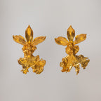 Aretes dorados con forma de orquídea Caucaea, mostrando su labelo ancho y textura delicada similar a un encaje natural.