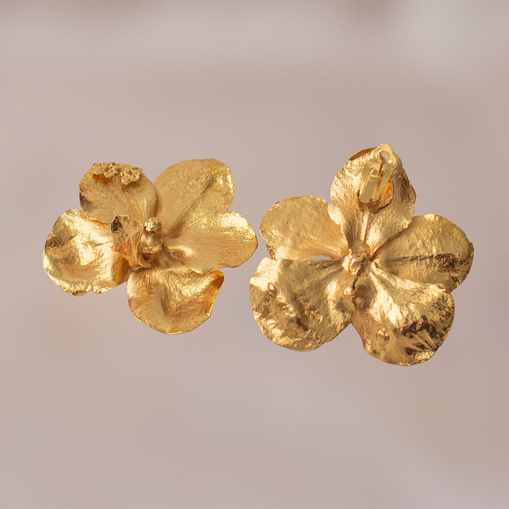 Vista lateral de aretes de orquídea Vanda dorada resaltando el cierre de alta calidad y la textura orgánica preservada de la flor.