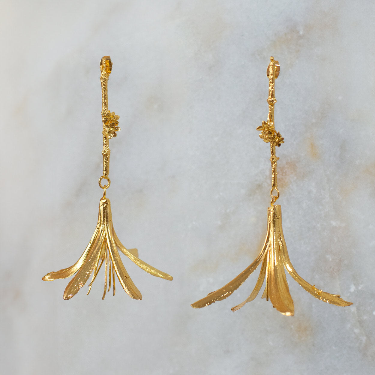 Aretes Lirio Agapanto Ramita Mini Flor Sauco en bronce bañado en oro de 24k, mostrando la combinación única de flores naturales con un diseño artesanal