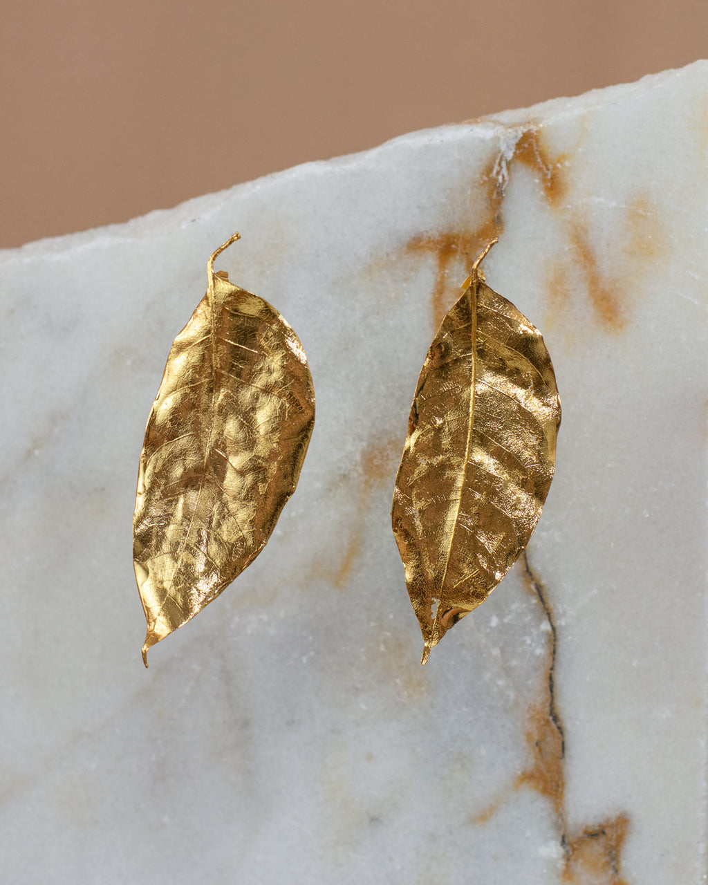 Aretes Topo Hoja Cúcuta en bronce bañado en oro de 24k, destacando la delicadeza y la forma única de las hojas naturales
