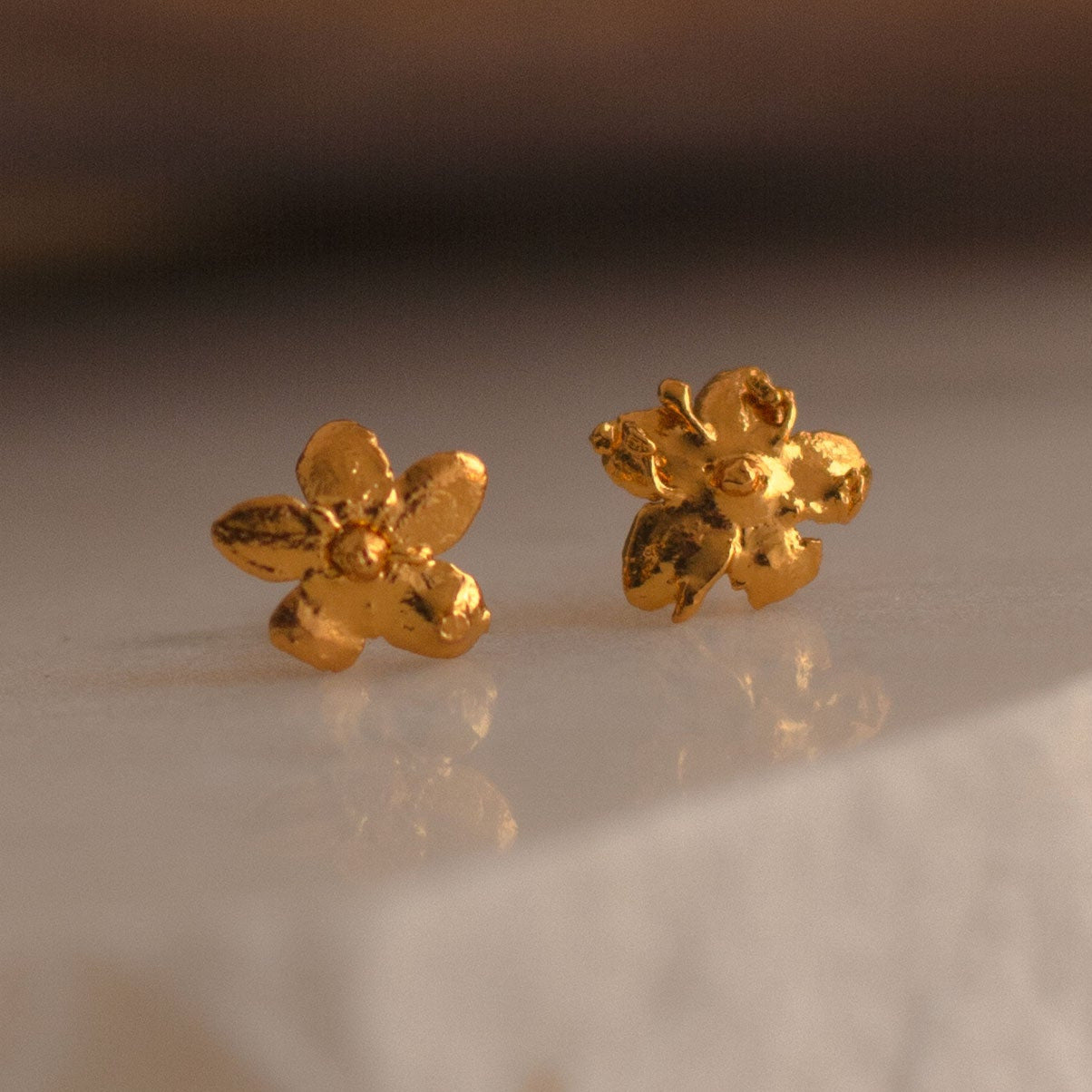 Aretes Topo Mini Flor Sauco en bronce bañado en oro de 24k, mostrando la delicadeza y la forma única de la flor natural.