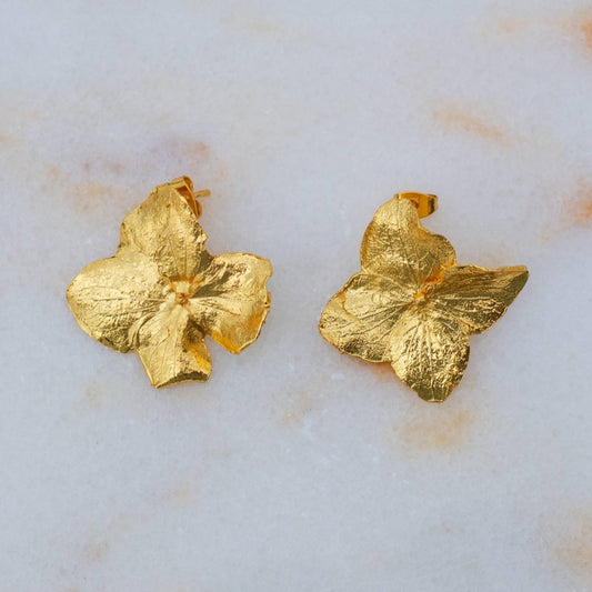 Aretes Topo Flor Hortensia en bronce bañado en oro de 24k, destacando la belleza única de las flores naturales de hortensia de nuestro jardín