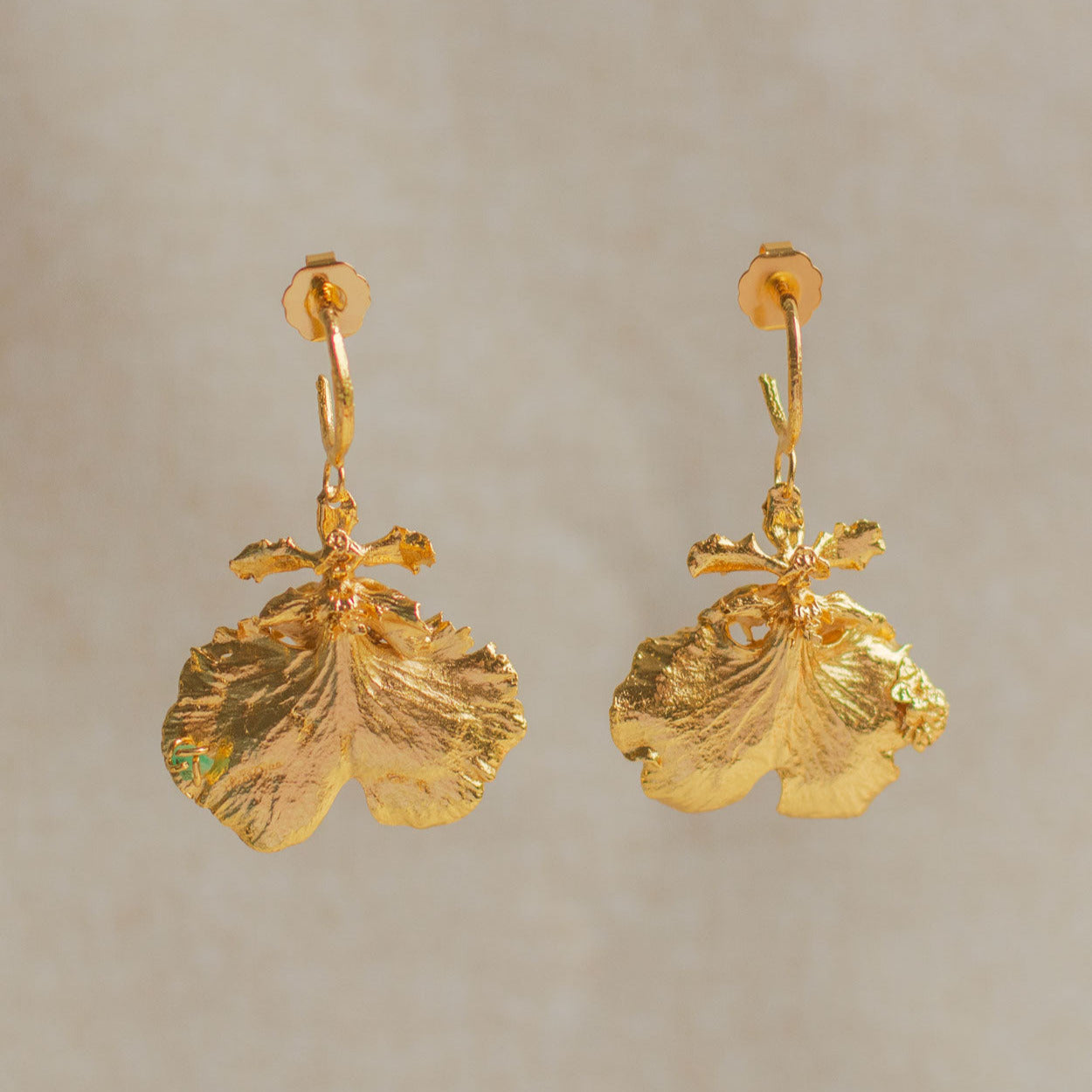 Aretes tipo candonga con orquídea Dama Danzante y ramita de pino bañados en oro con esmeraldas