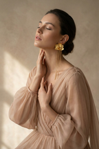 Detalle de aretes con movimiento: flor natural preservada y cadena dorada, accesorio elegante para noche o eventos.