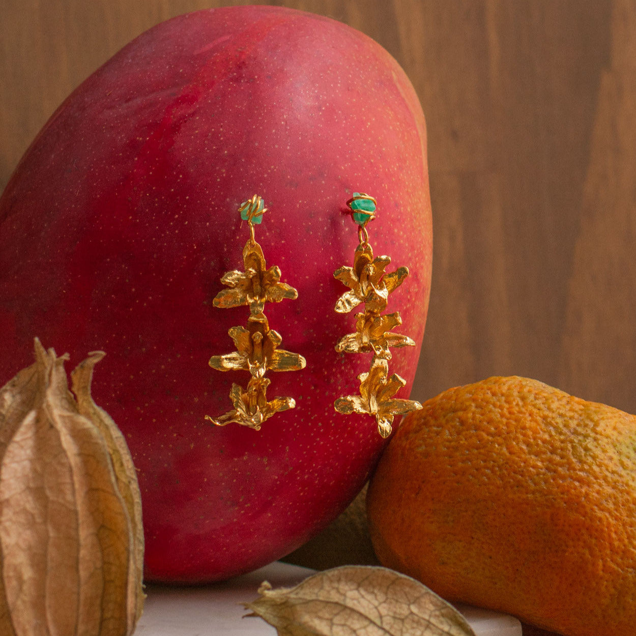 Aretes largos con orquídea Maxilaria y esmeraldas colombianas en oro 24k

