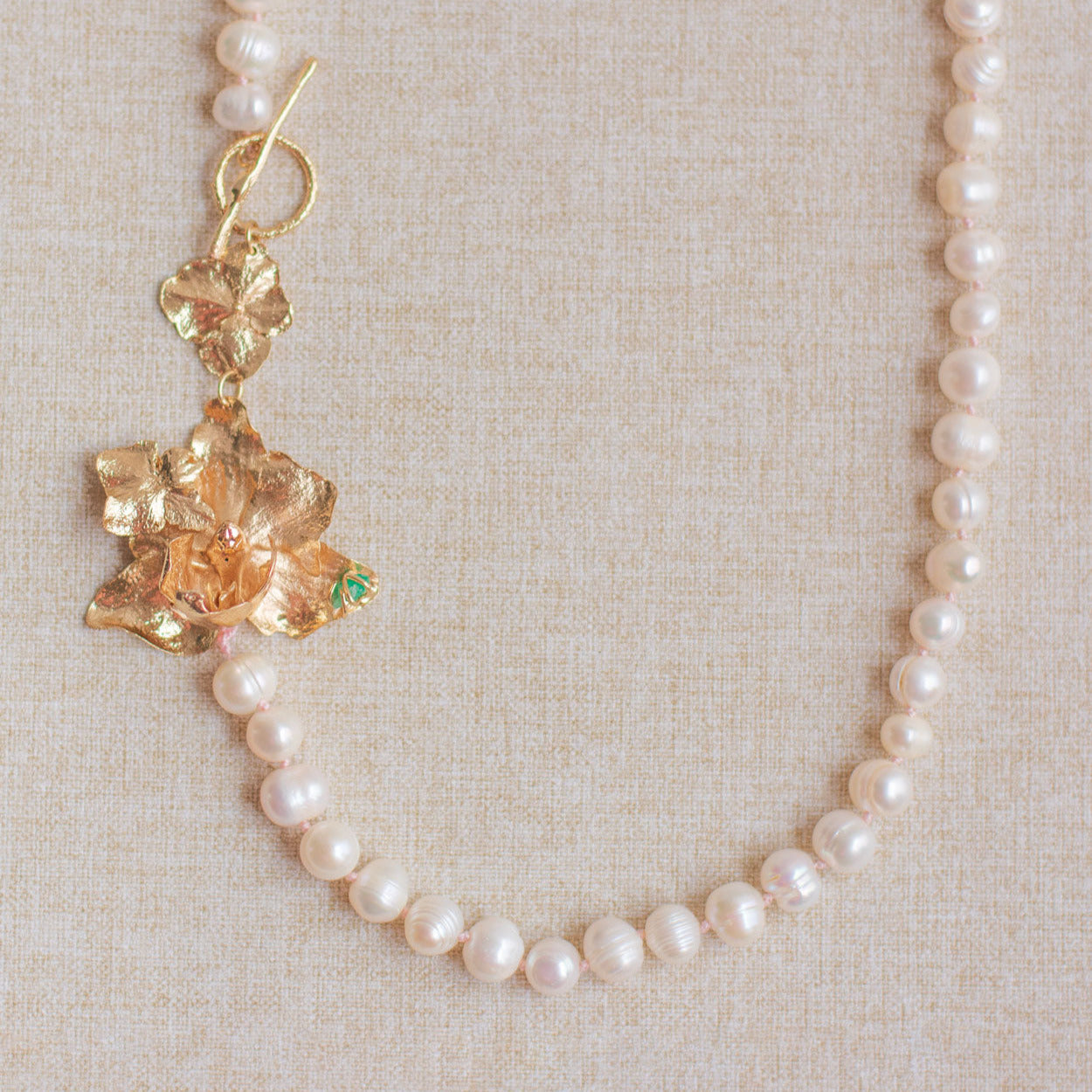 Joya artesanal con hortensias, esmeralda y baño de oro rosa