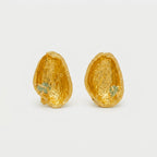 Joyería botánica Colombia: aretes topo cáscara pistacho oro 24k con esmeralda colombiana en bruto, fundición orgánica directa, naturaleza inmortalizada