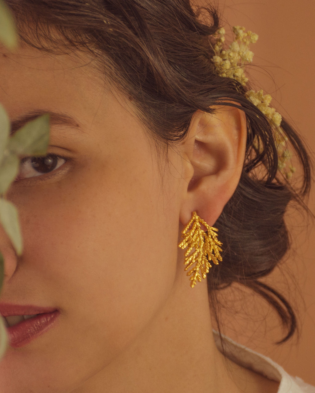 Joyería artesanal de aretes topo con hoja de pino inmortalizada en oro de 24k