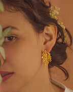 Joyería artesanal de aretes topo con hoja de pino inmortalizada en oro de 24k