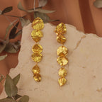 Aretes Largos Tres Eucaliptos en bronce bañado en oro de 24k, resaltando la delicadeza y el diseño único de las hojas naturales