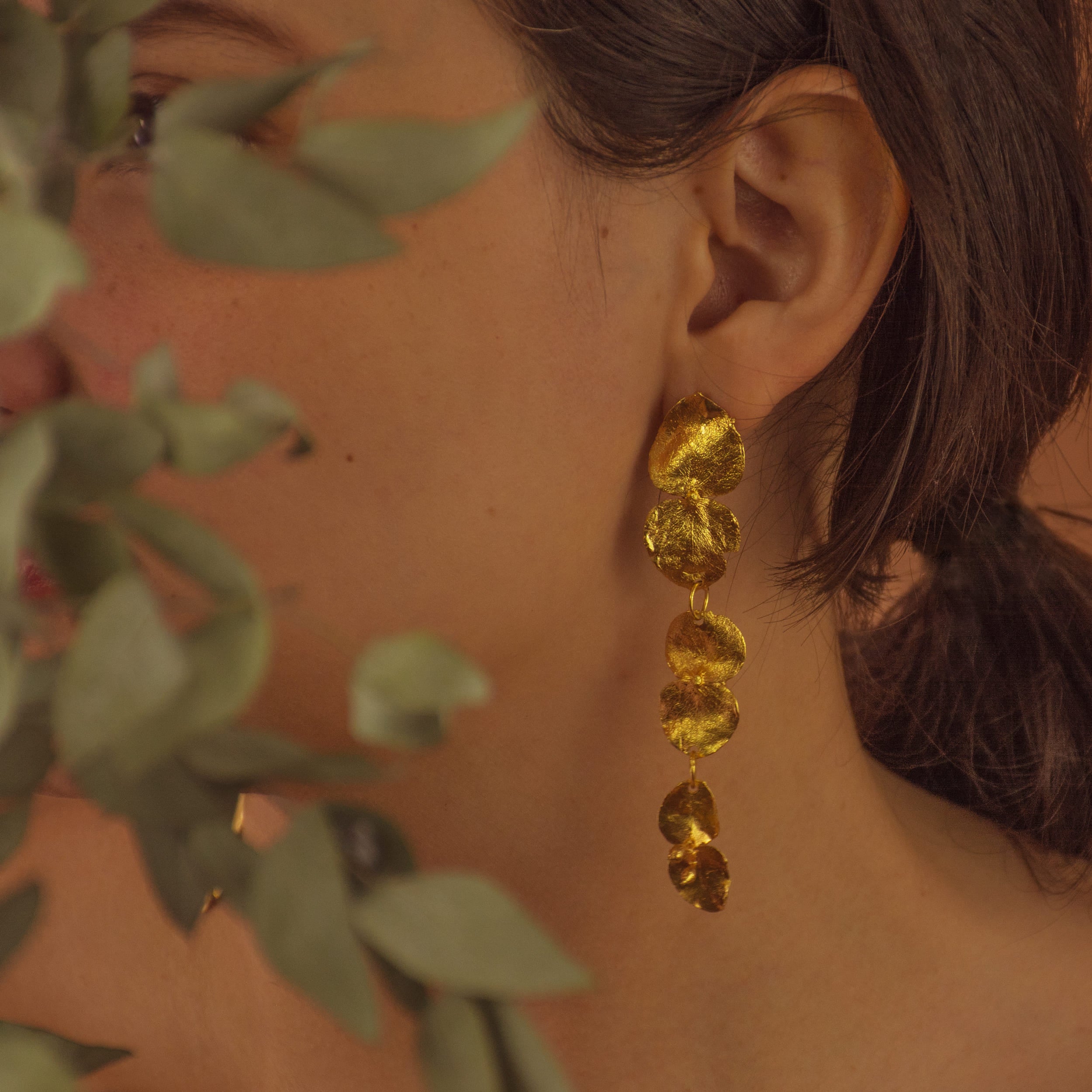 Aretes Largos Tres Eucaliptos en bronce bañado en oro de 24k, resaltando la delicadeza y el diseño único de las hojas naturales