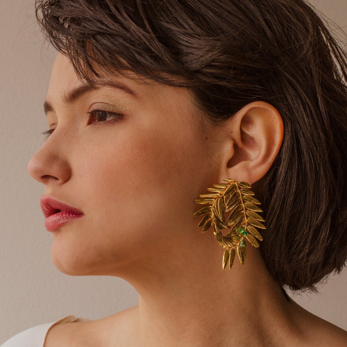 Joyería artesanal de aretes espiral con hojas de pino romeron y esmeralda en oro de 24k
