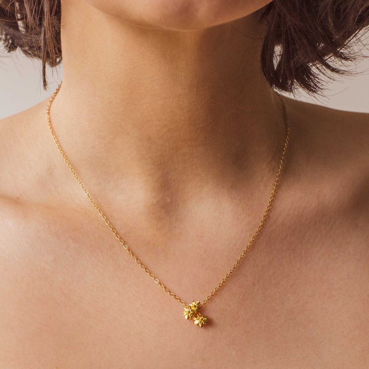 Gargantilla Ramita Mini Flor Sauco en bronce bañado en oro de 24k, destacando la belleza y delicadeza de las flores naturales