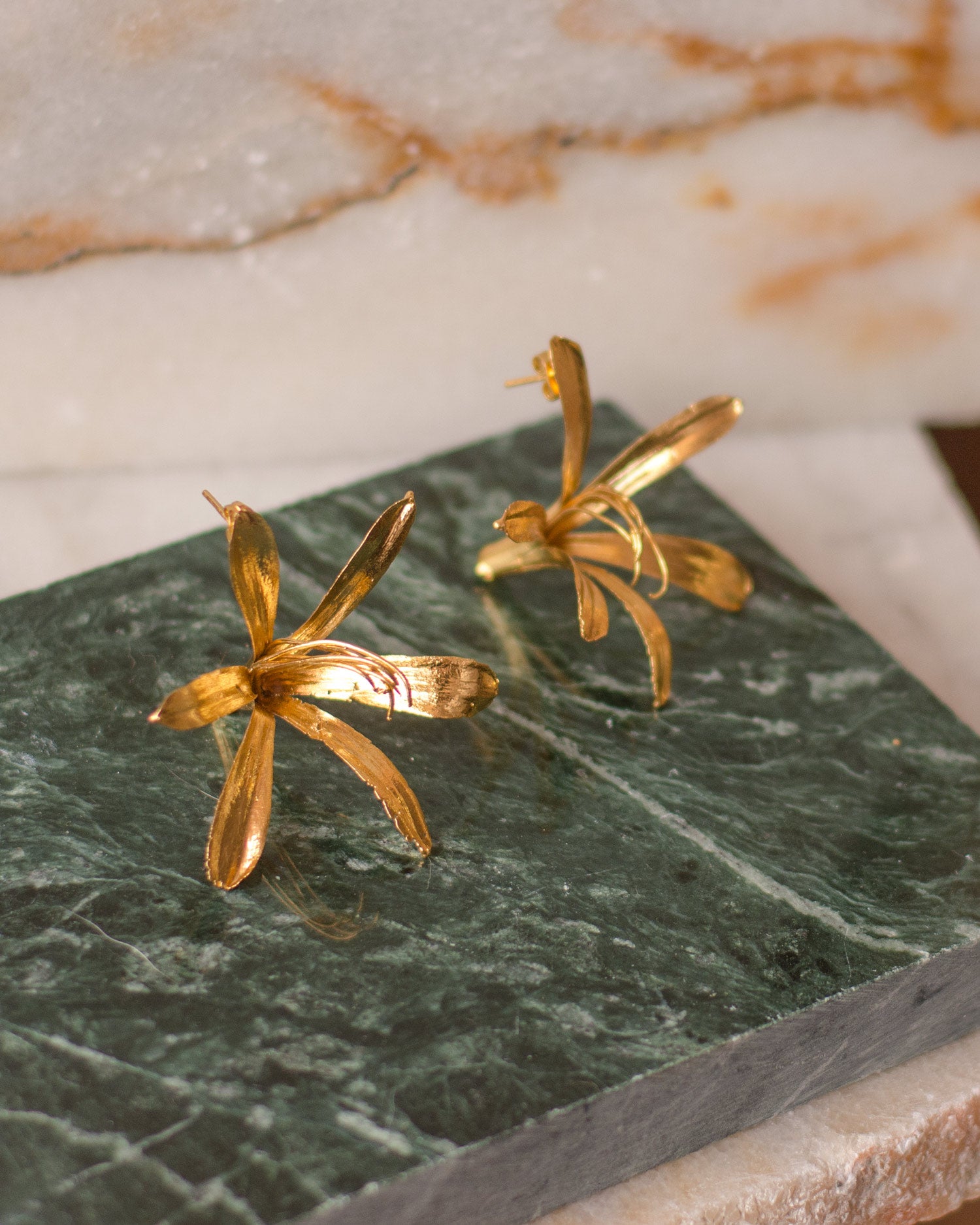 Aretes Topo Lirio Agapanto en bronce bañado en oro de 24k, destacando la belleza y singularidad de las flores naturales.