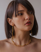 Collar Choker Ramita Palma Coco Esmeralda en bronce bañado en oro de 24k, destacando la textura natural de la ramita y el brillo verde de las esmeraldas