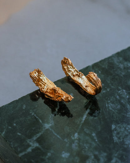 Aretes Topo Corteza en bronce bañado en oro de 24k, mostrando la textura única de la corteza de pino recolectada en Bogotá