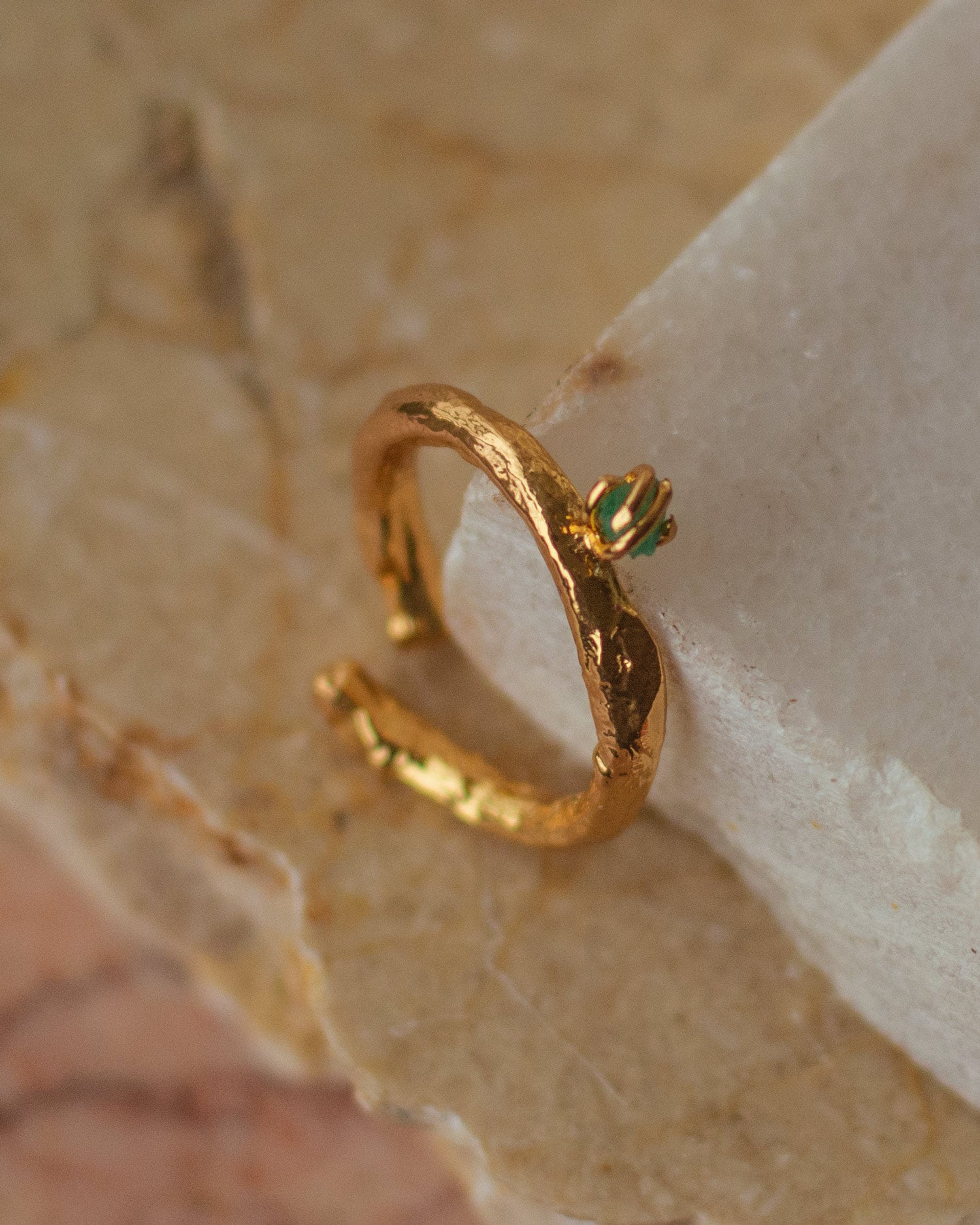Anillo Ramita con Esmeralda en bronce bañado en oro de 24k, destacando la textura natural de la ramita y el brillante verde de la esmeralda
