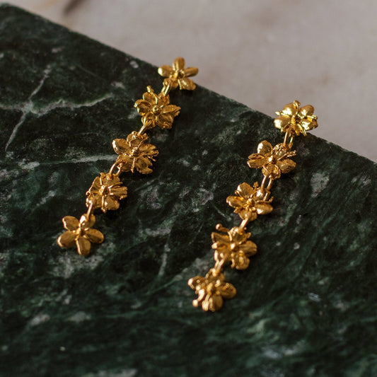 Aretes Cinco Saucos en bronce bañado en oro de 24k, mostrando la elegancia y la forma única de las flores de sauco naturales